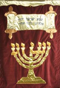weinrotes Banner mit goldener Torarolle (hebräische Aufschrift) und goldener Menora, in der der Name Jeshua eingearbeitet ist